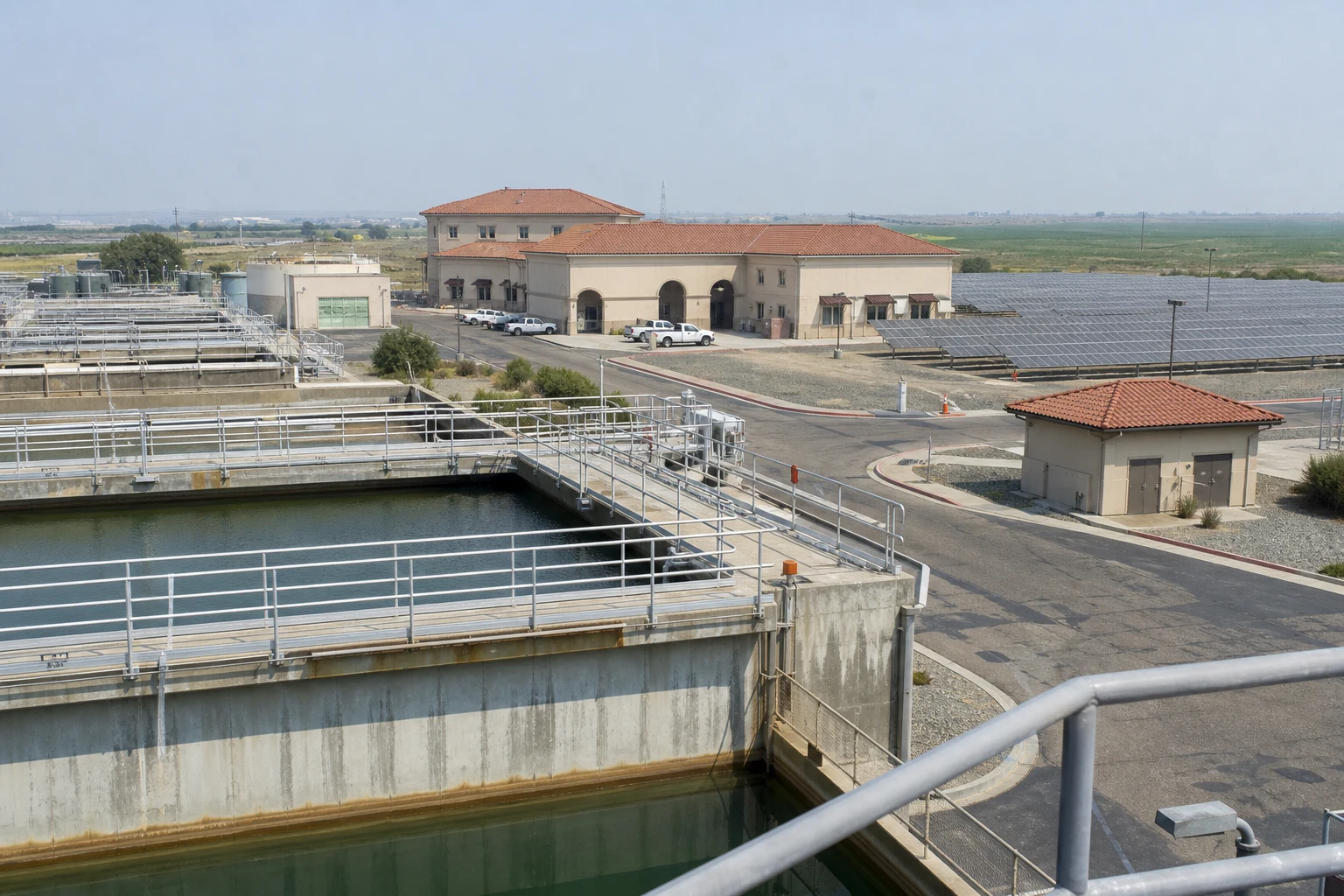 Operating water treatment facility with process basins and solar infrastructure